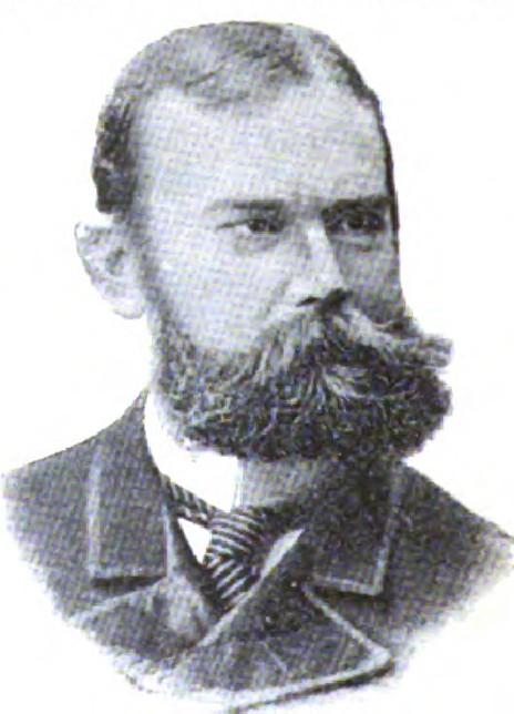 Man with wavy hair and mustache in formal attire