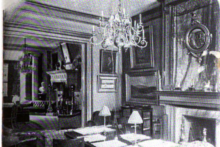A vintage interior photograph of the Players Club Reading Room, showing a long table, a fireplace with a tapestry and mirror above it, and a view into the adjacent Middle Room.