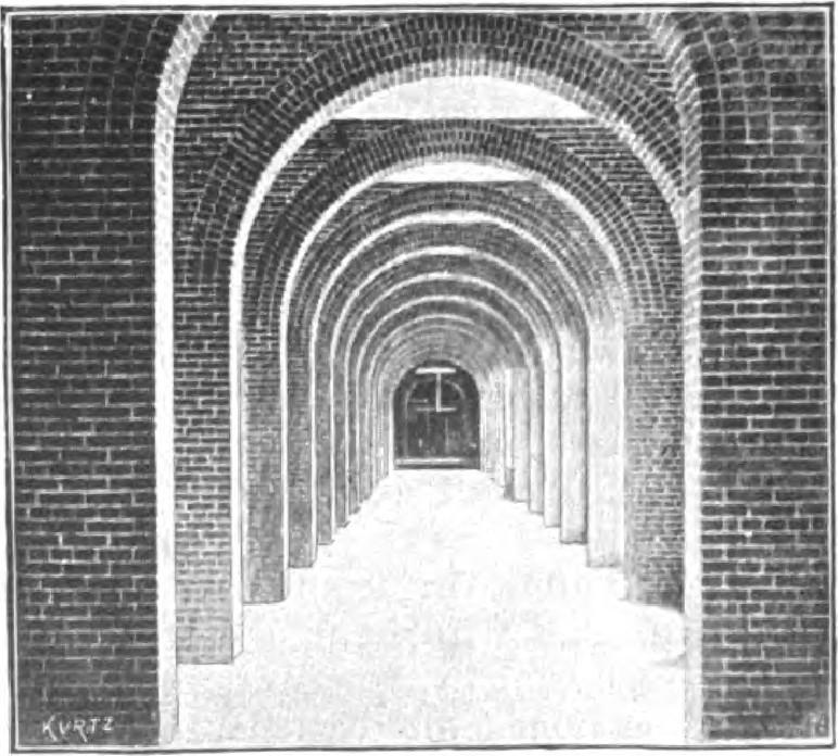 Series of brick archways forming long corridor with repetitive architectural pattern