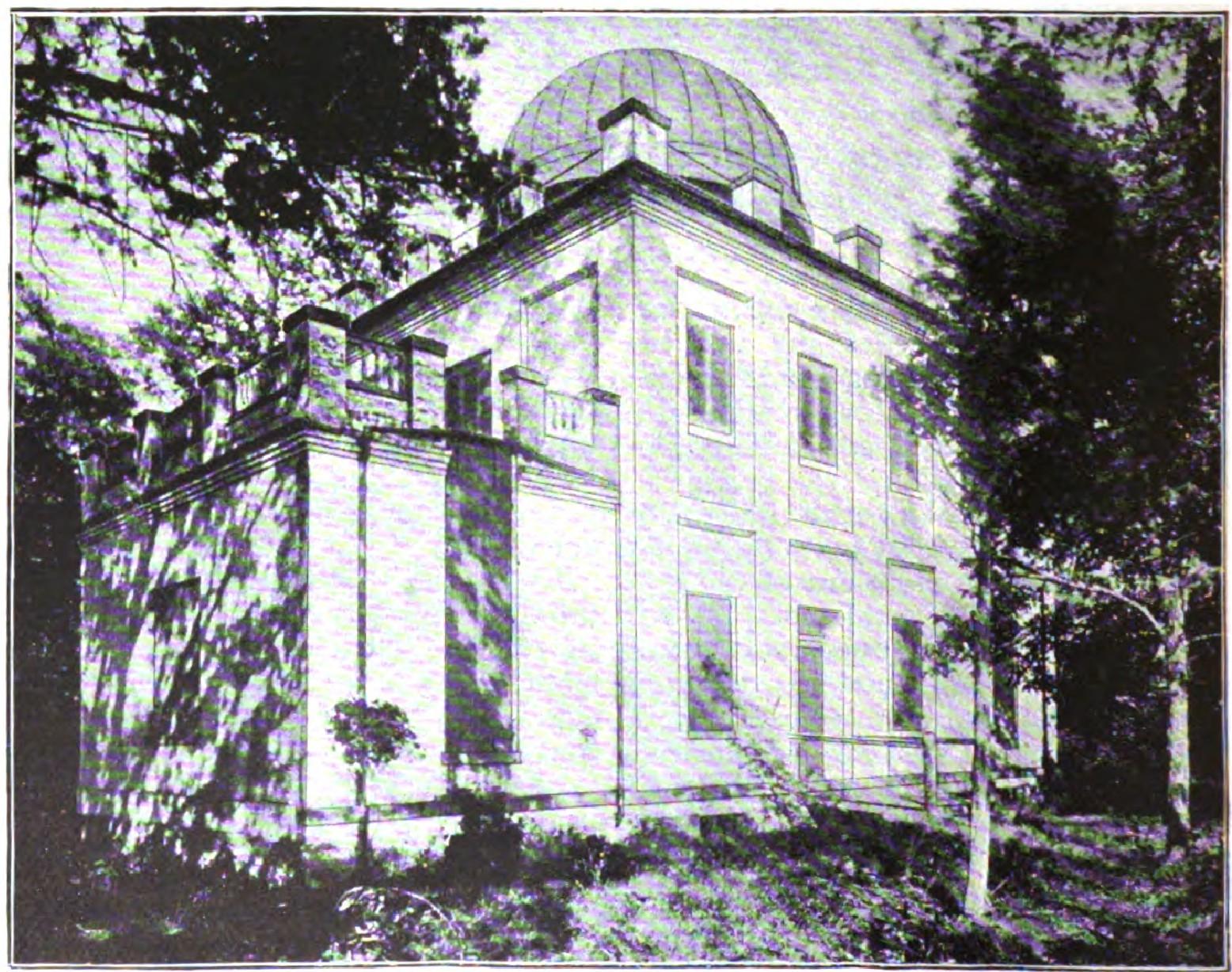 White observatory building with dome surrounded by mature trees