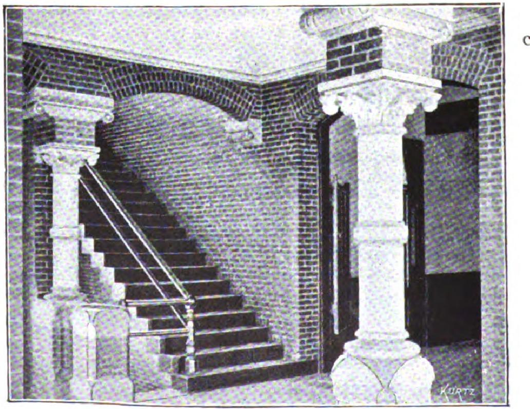 Brick interior with white columns and staircase featuring classical design elements